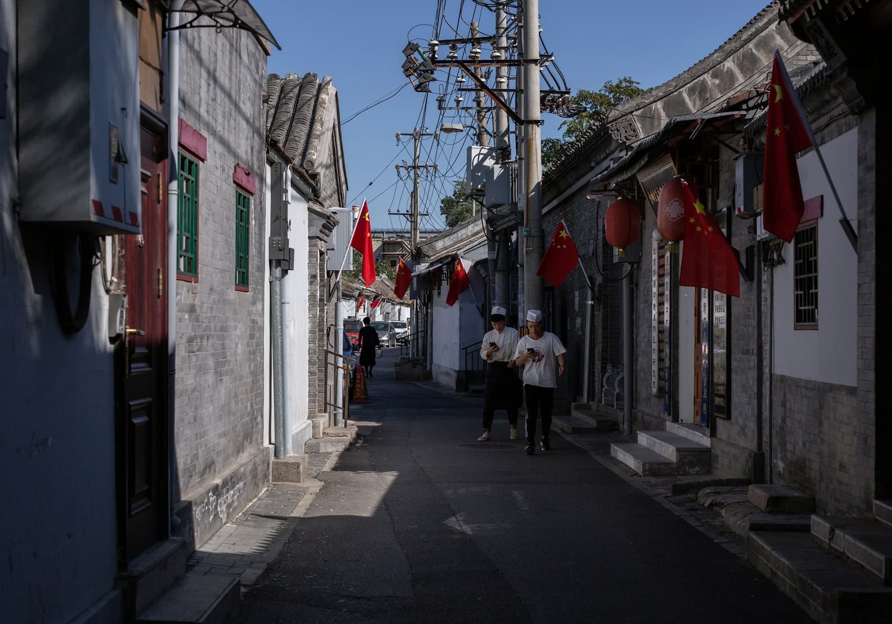 Two people walking through a traditional Beijing hutong alley