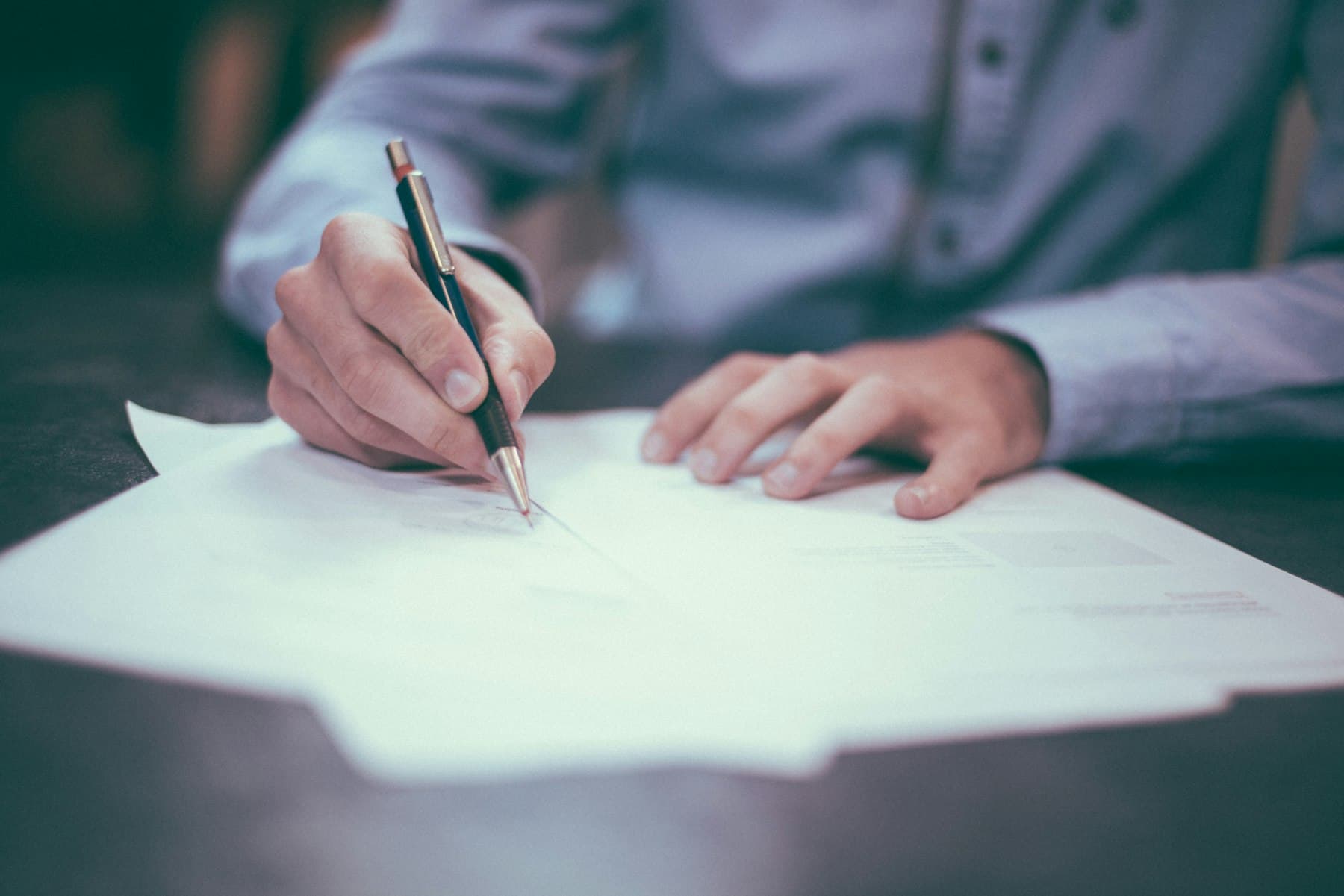 Hands reviewing financial documents and statements at a desk in soft daylight