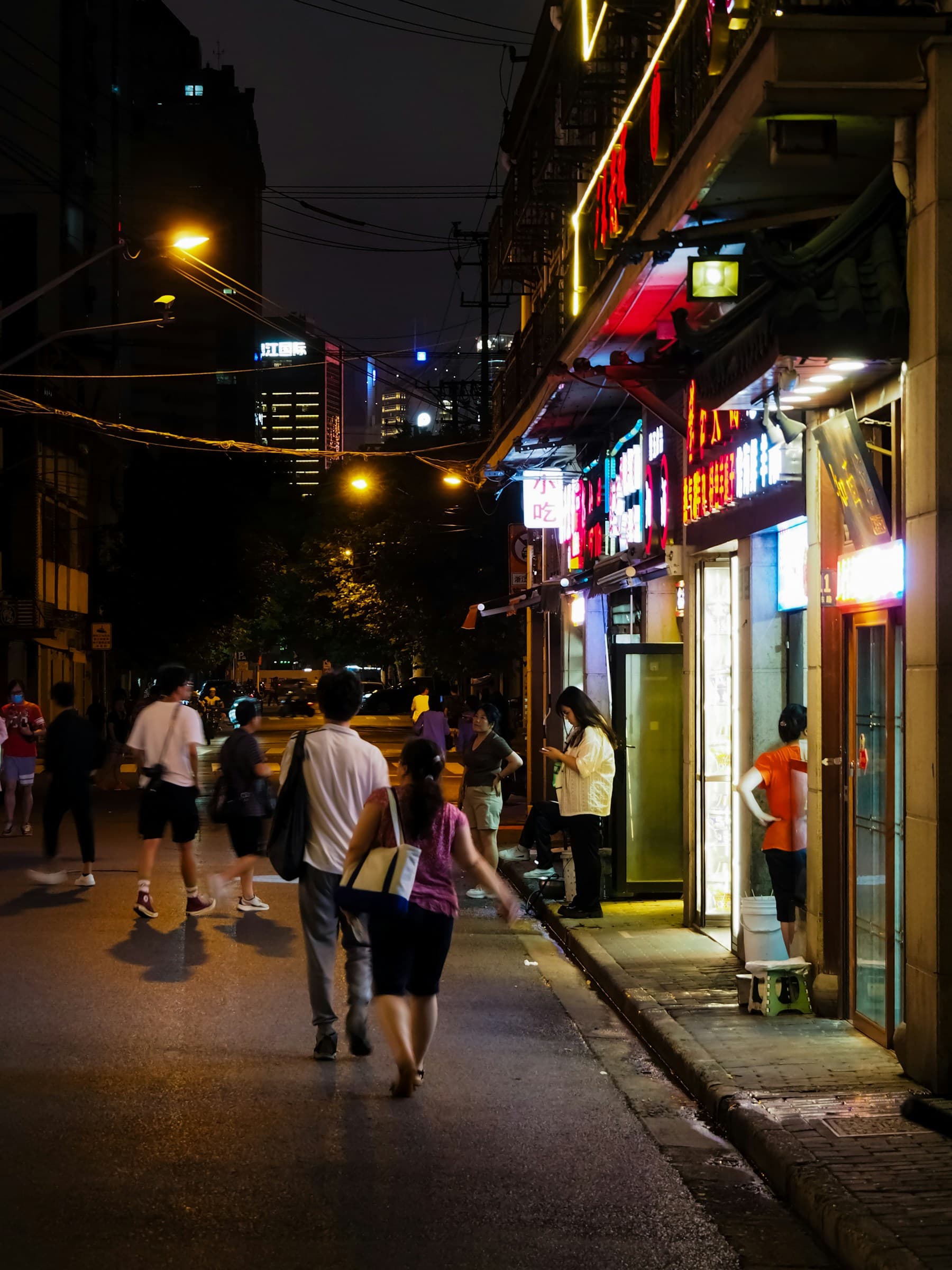 A lively Shanghai street at night with Chinese shop signs and pedestrians